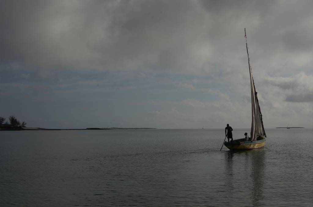 Foto do horizonte, na foto mas e céu com muitas nuvens, a direita é possível ver um barco com pessoas dentro.