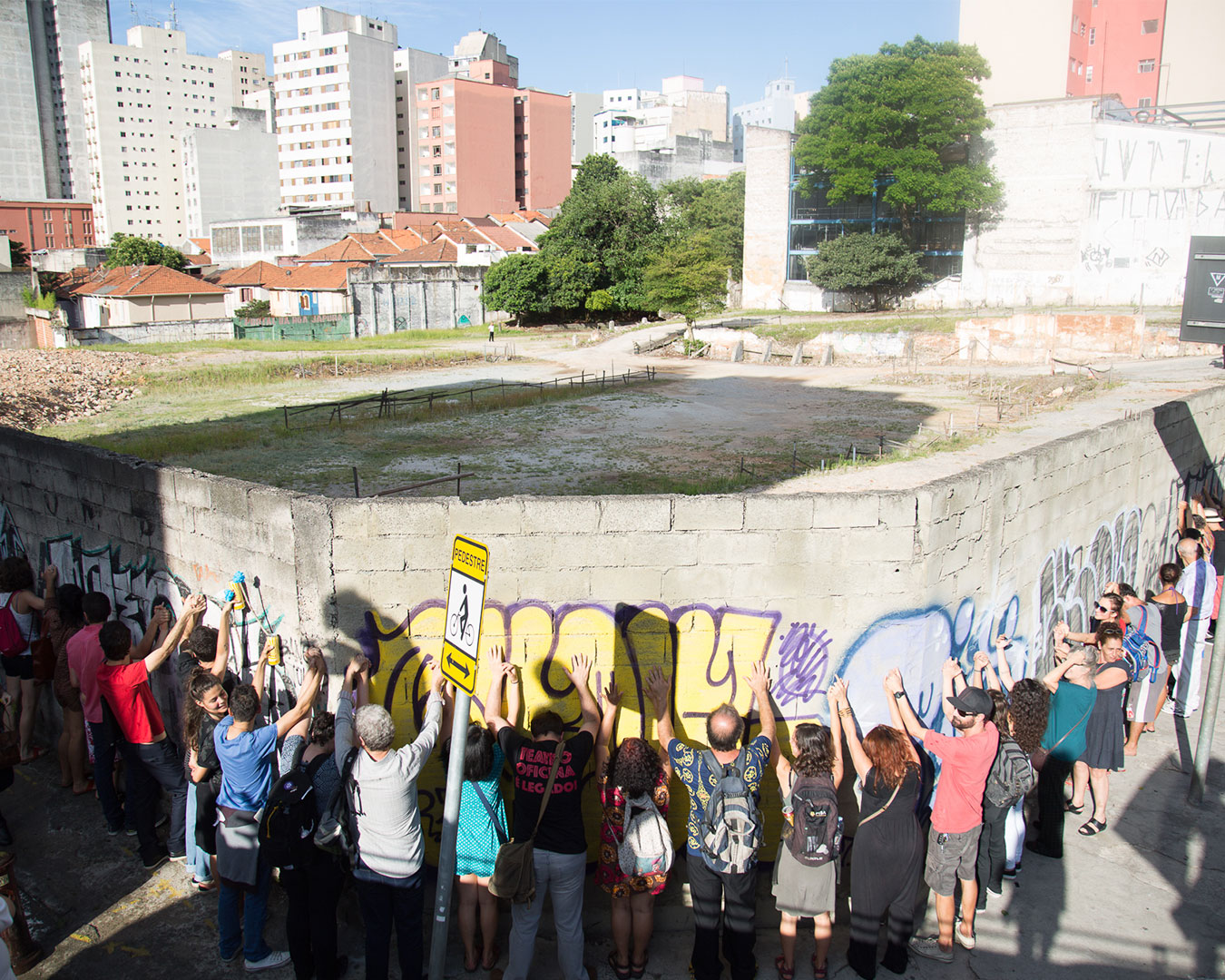 Pessoas rodeiam os muros do terreno ao lado do teatro oficina.